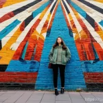 벽화여행과 기념품 - **Prompt:** A young female traveler in her late 20s, dressed in stylish but comfortable layered clot...